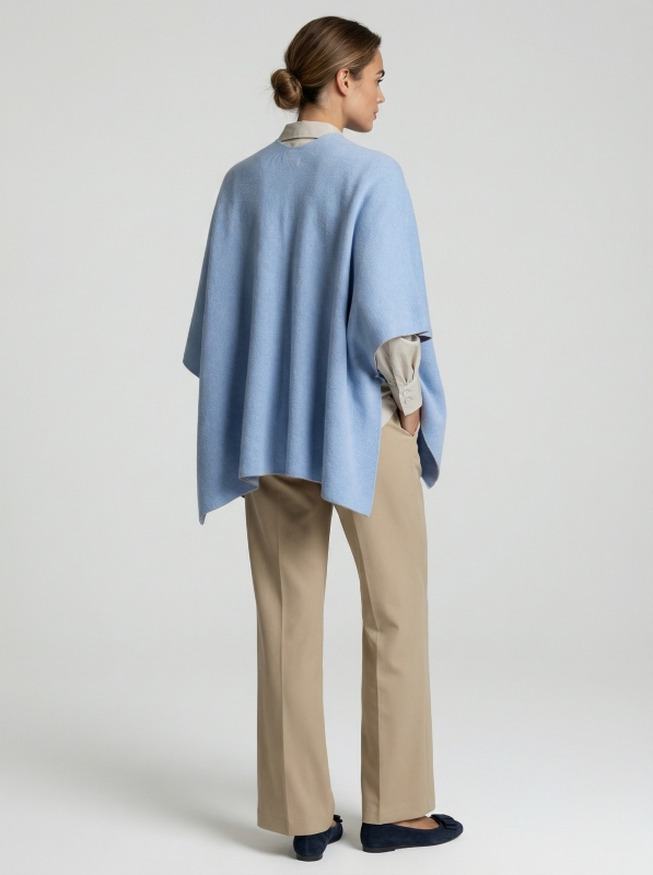 Junge Dame trägt ein gestricktes Cape in hellblau mit grauer Innenseite