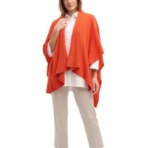 Junge Dame trägt gestricktes feminines Cape in orange