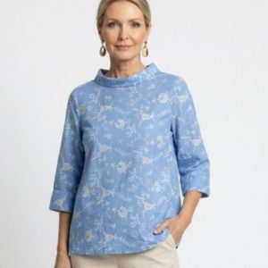 Frau trgät hellblaue Bluse mit weiser Stickerei