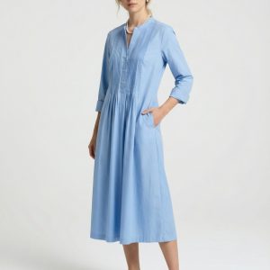 Frau trägt ein hellblaues, wadenlanges Kleid mit Faltendetails am oberen Vorderteil